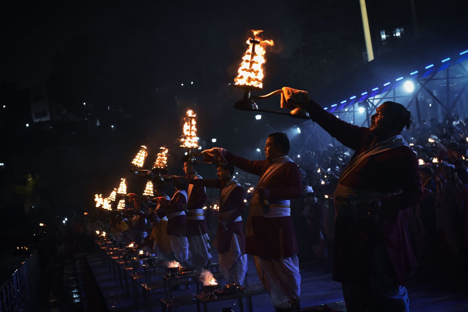 A captivating Ganga Aarti ceremony with priests holding lit lamps by the Ganges River in Rishikesh, India.