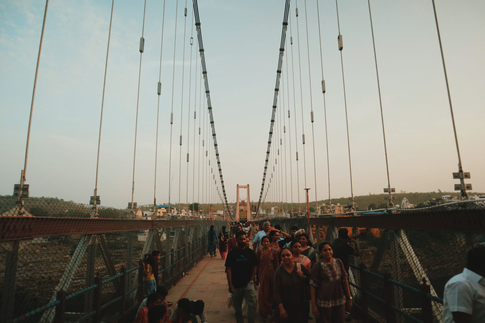 A bustling suspension bridge filled with people at sunset, capturing vibrant daily life.