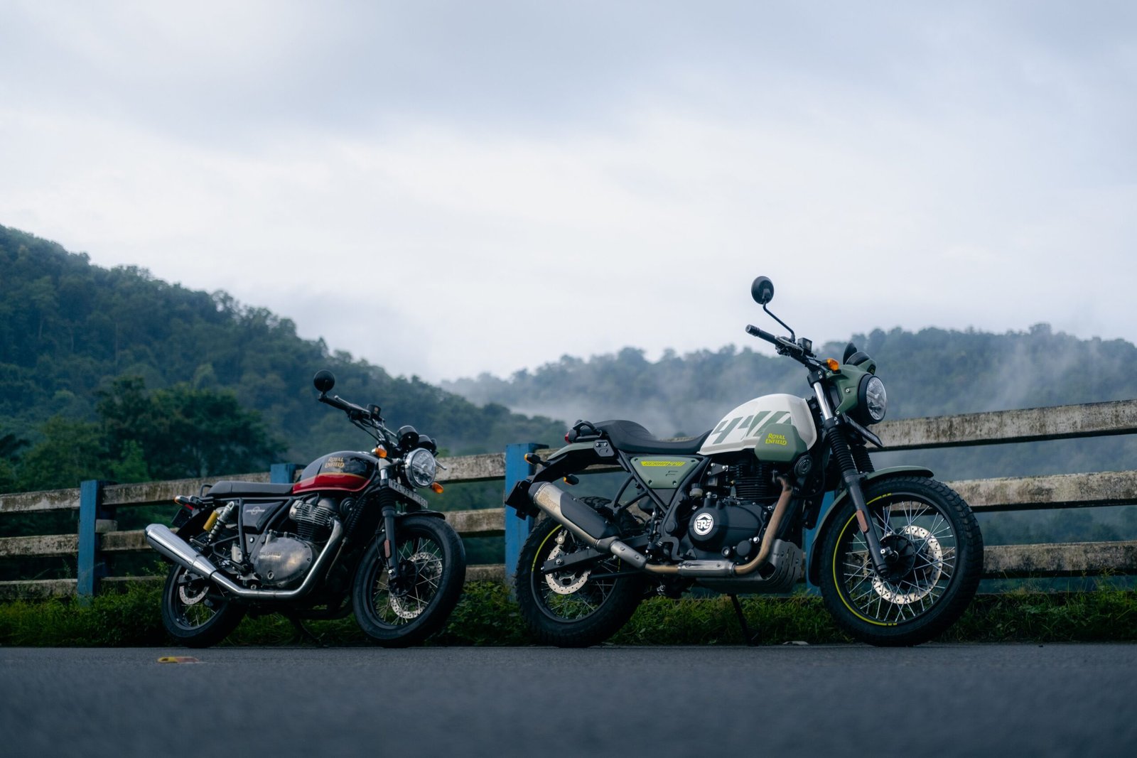 Two vintage motorcycles parked against a misty mountain backdrop in Pariyaram, Kerala.
