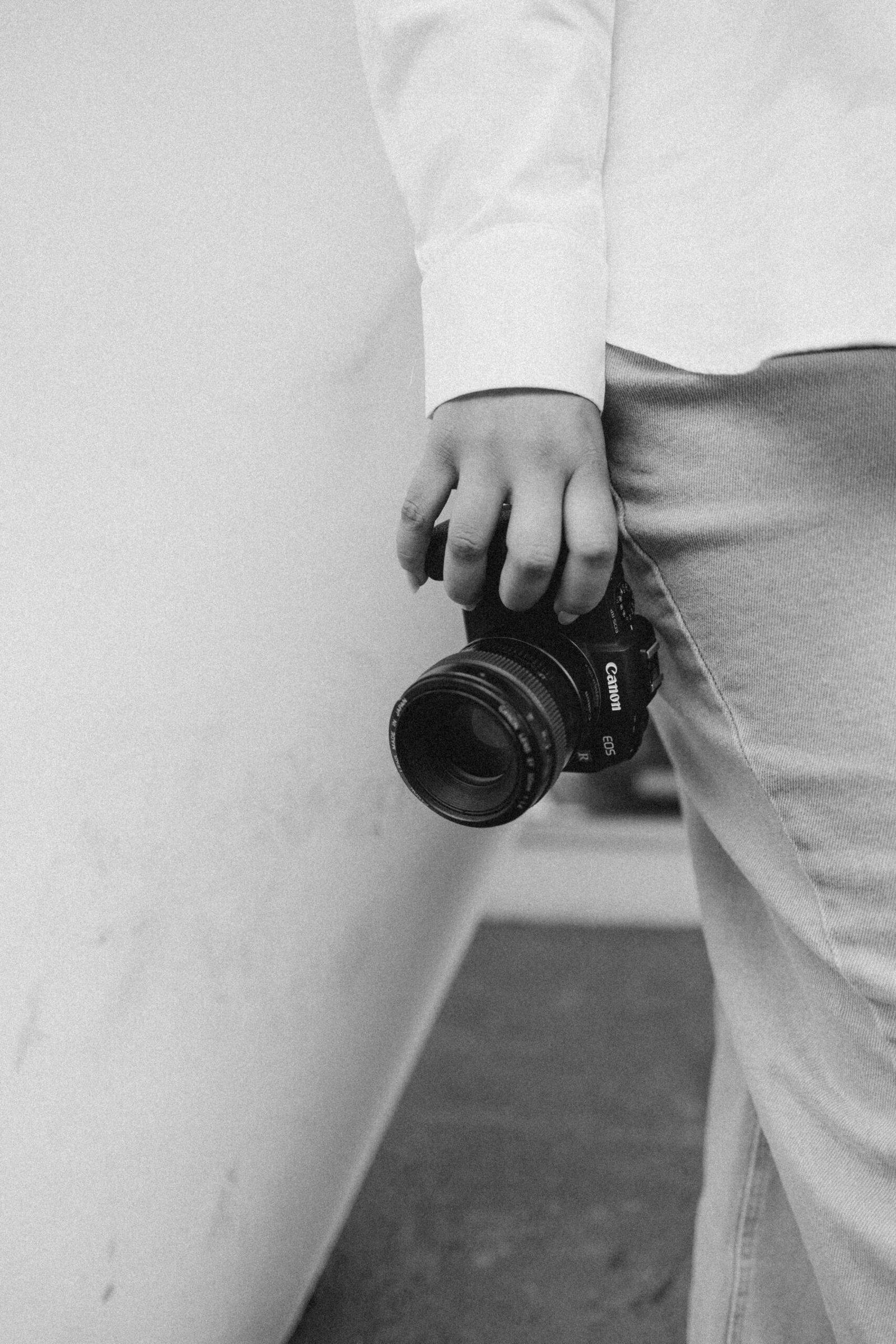 Monochrome image showcasing a person holding a camera, emphasizing minimalism and photography themes.