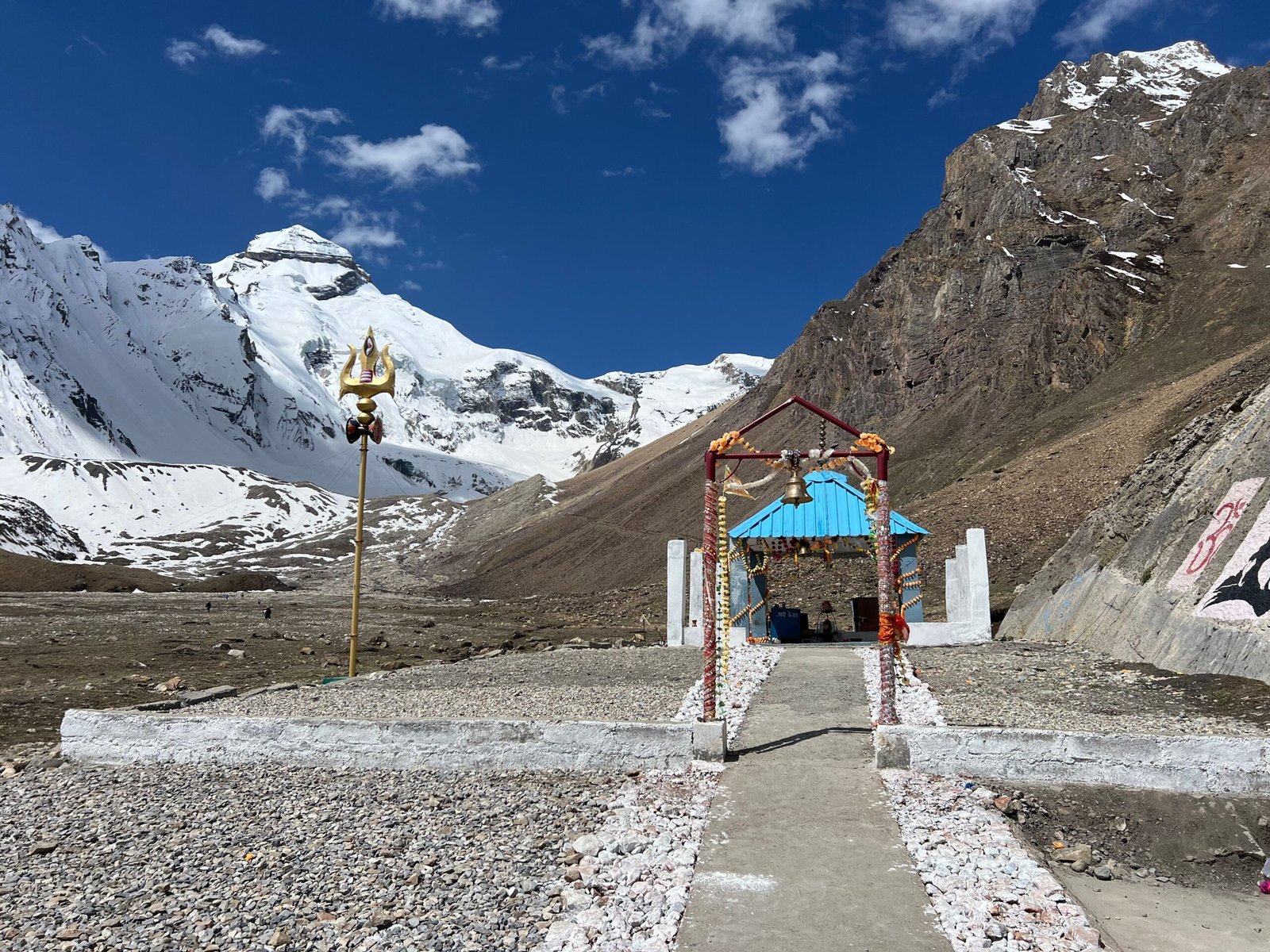 Remote temple surrounded by majestic snowy mountains under a clear blue sky.
