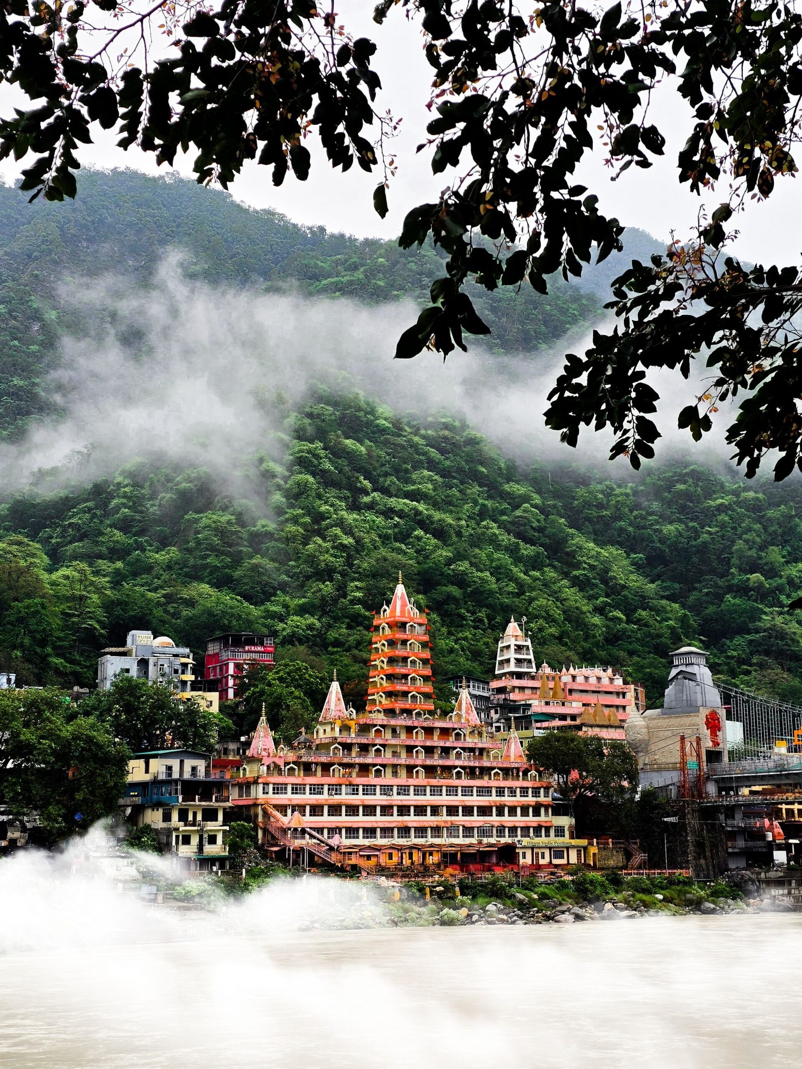 Scenic view of Trimbakeshwar temple amidst mist and lush green hills in Rishikesh, India.